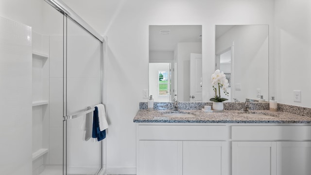 bathroom featuring double vanity, a shower stall, and a sink