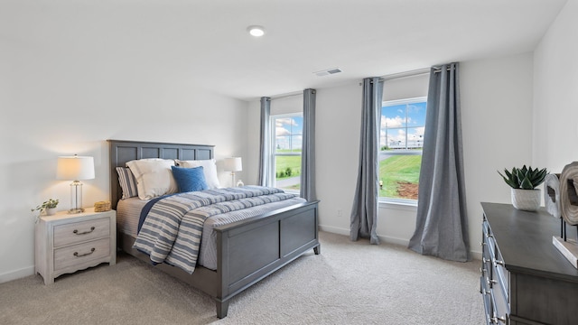 bedroom with visible vents, light carpet, baseboards, and multiple windows