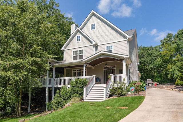 view of front of property featuring covered porch, a front lawn, a chimney, and stairs