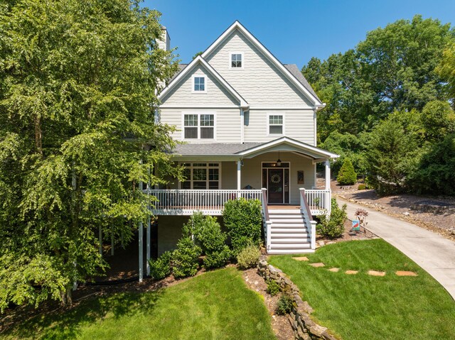 view of front of property featuring covered porch, a front lawn, and stairway