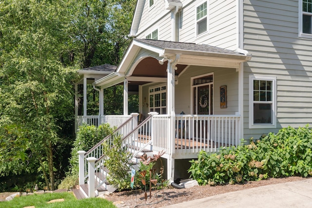 doorway to property featuring a porch and roof with shingles