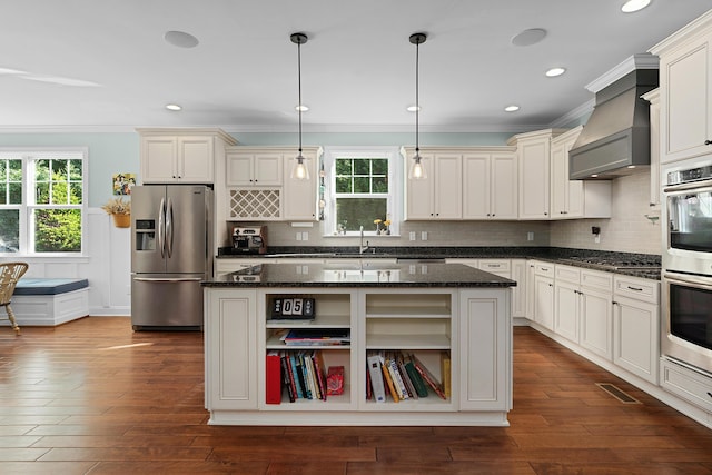 kitchen with dark wood-style flooring, a sink, a kitchen island, appliances with stainless steel finishes, and crown molding