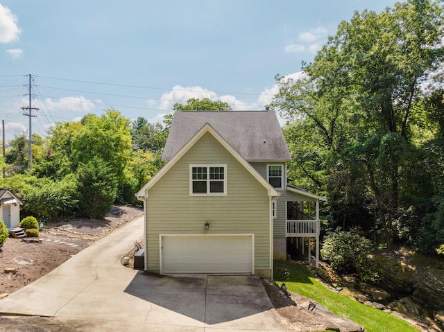 view of home's exterior featuring concrete driveway and roof with shingles