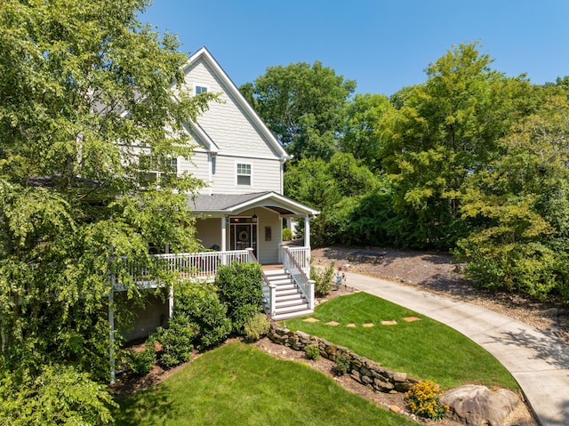 view of front of home with covered porch, stairway, a front lawn, and concrete driveway