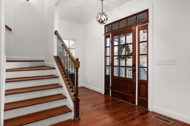 foyer with visible vents, dark wood finished floors, stairway, ornamental molding, and a notable chandelier