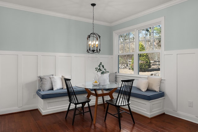 dining space with a decorative wall, ornamental molding, breakfast area, wood-type flooring, and an inviting chandelier