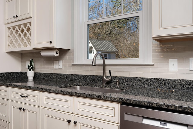 kitchen with a sink, white cabinetry, backsplash, dishwasher, and dark stone countertops