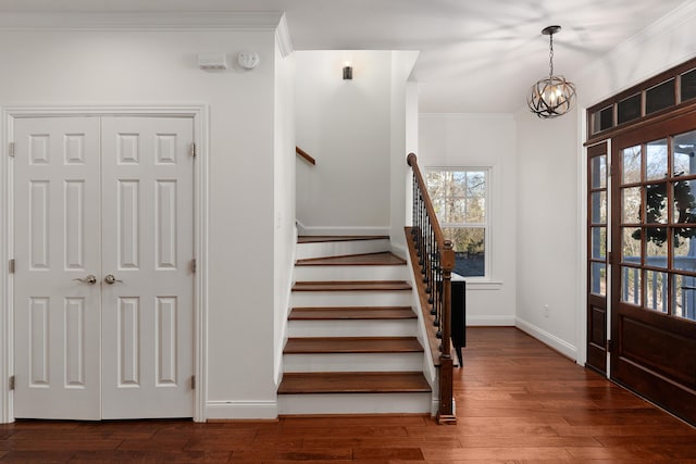 foyer with a notable chandelier, baseboards, stairway, hardwood / wood-style floors, and crown molding