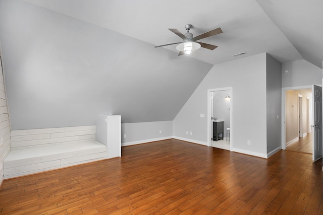 additional living space with lofted ceiling, visible vents, hardwood / wood-style floors, ceiling fan, and baseboards