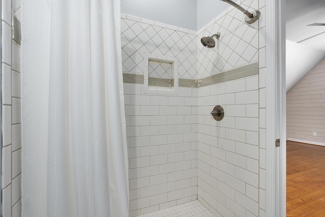 bathroom featuring lofted ceiling, tiled shower, and wood finished floors