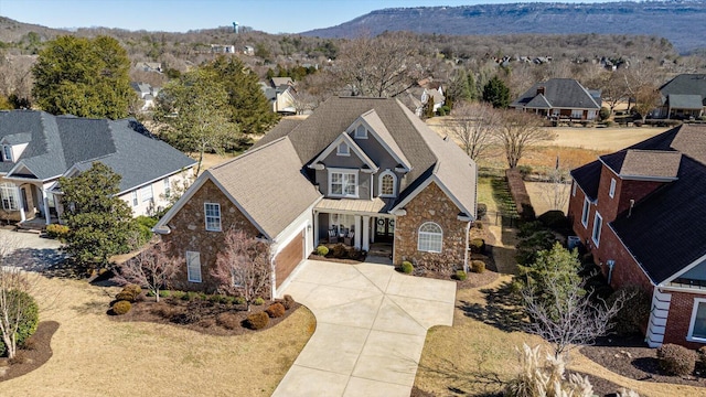 view of front of house with driveway, stone siding, a residential view, and a mountain view