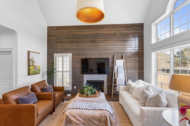 living area with wooden walls, a fireplace, and high vaulted ceiling