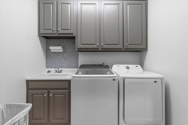 clothes washing area featuring cabinet space, independent washer and dryer, and a sink