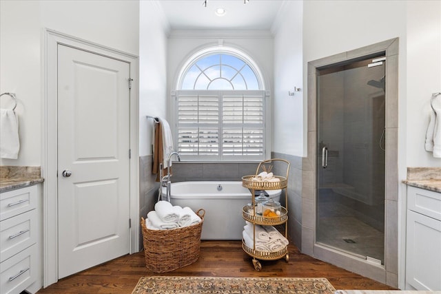 bathroom with a soaking tub, ornamental molding, a stall shower, vanity, and wood finished floors