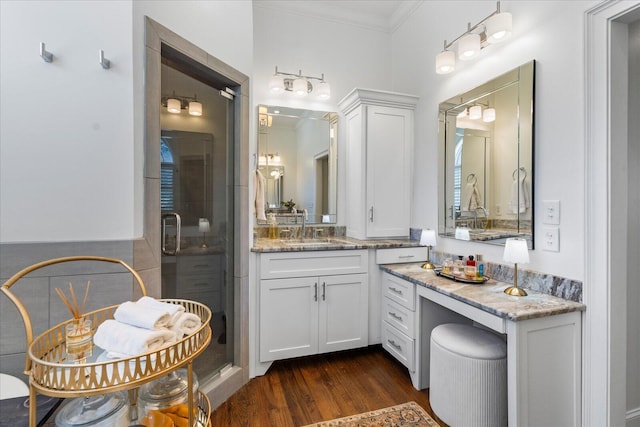 bathroom featuring ornamental molding, wood finished floors, vanity, and a shower stall