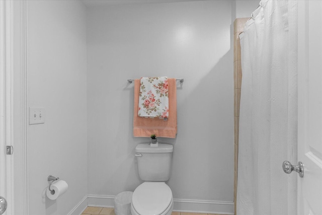 bathroom with curtained shower, toilet, and baseboards