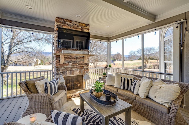 sunroom with beam ceiling and a stone fireplace