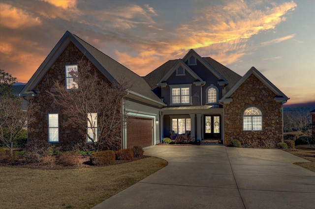 traditional-style home featuring concrete driveway, stone siding, and an attached garage