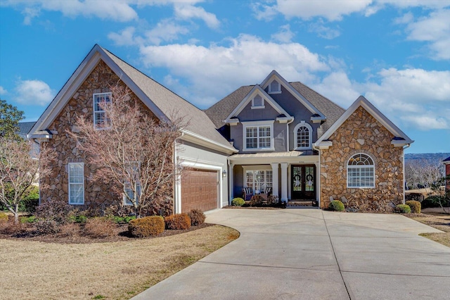 view of front of home with stone siding, concrete driveway, french doors, and an attached garage