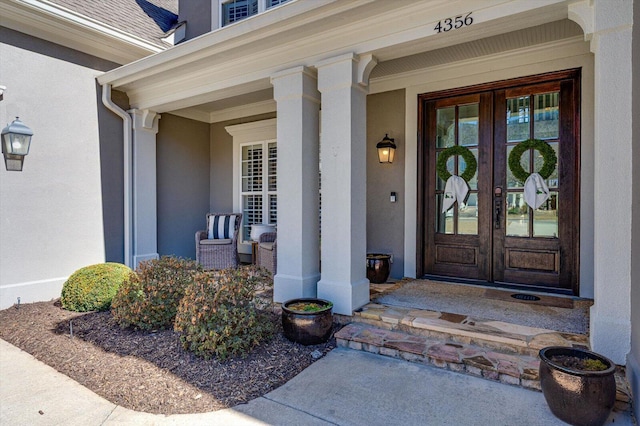 property entrance featuring french doors, roof with shingles, and stucco siding