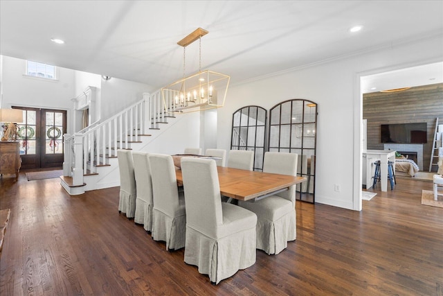 dining area with dark wood finished floors, ornamental molding, stairway, french doors, and a chandelier