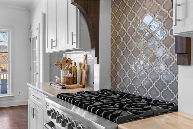 kitchen with stainless steel stove, dark wood-style flooring, white cabinetry, ornamental molding, and decorative backsplash