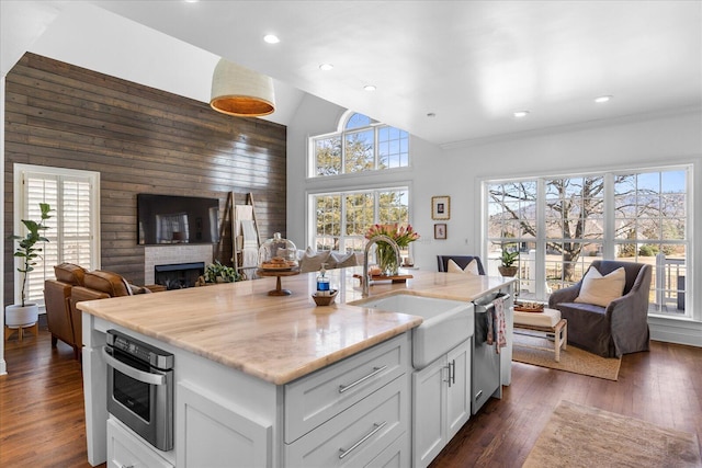 kitchen with an island with sink, white cabinets, stainless steel dishwasher, and open floor plan