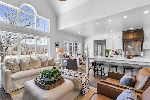 living room with high vaulted ceiling, light wood finished floors, and recessed lighting