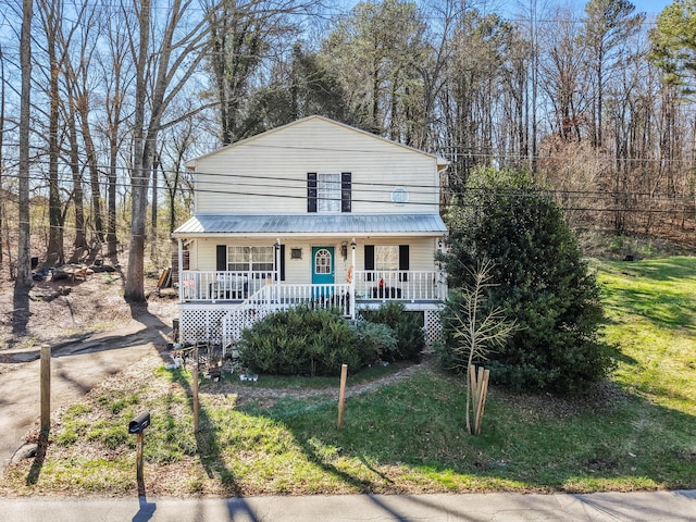 view of front of property featuring covered porch, metal roof, and a front lawn