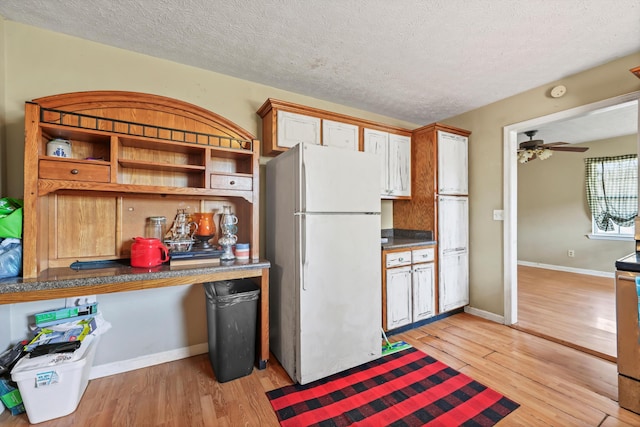 kitchen with a textured ceiling, light wood finished floors, freestanding refrigerator, and baseboards