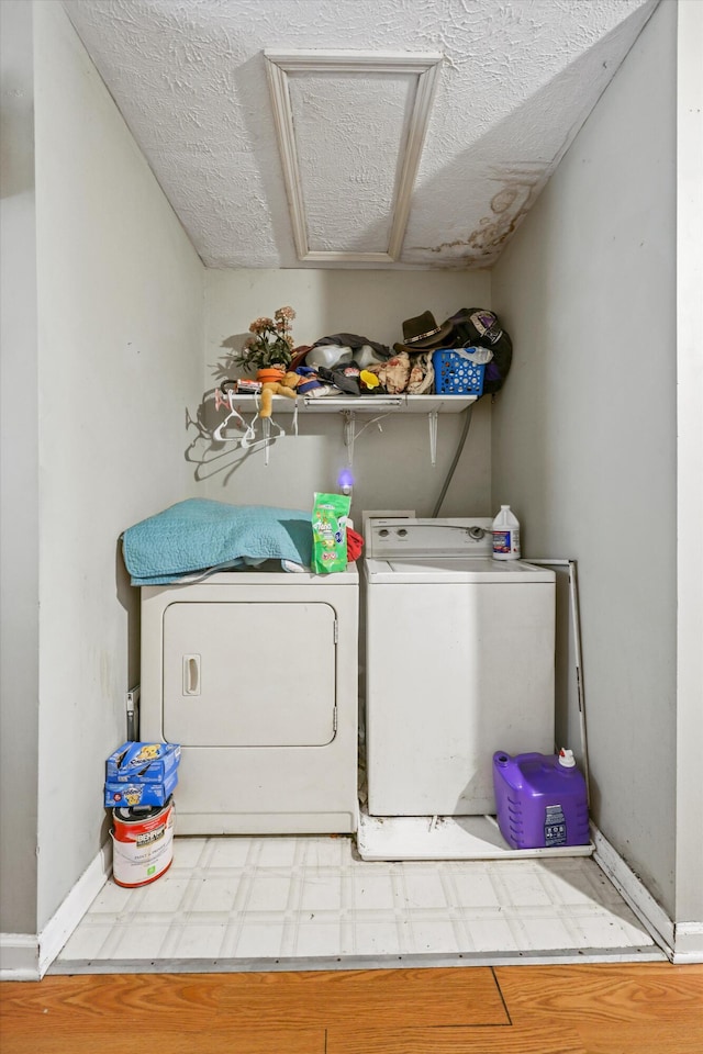 washroom with a textured ceiling, baseboards, washer and dryer, and tile patterned floors