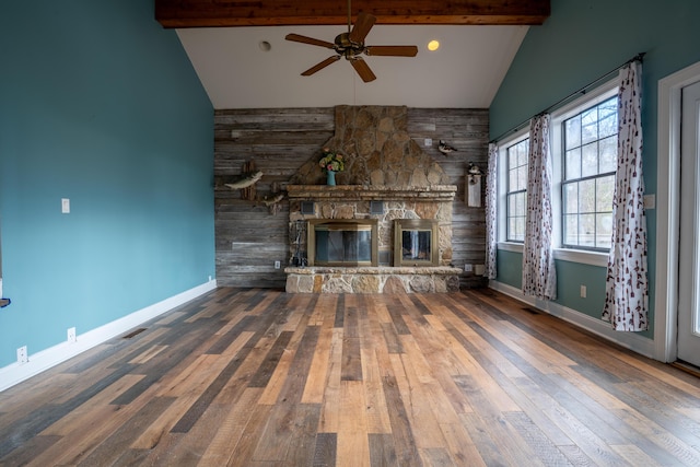 unfurnished living room featuring baseboards, beamed ceiling, wood finished floors, a fireplace, and high vaulted ceiling