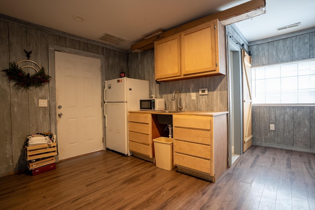 kitchen with white appliances, visible vents, a sink, and wood finished floors