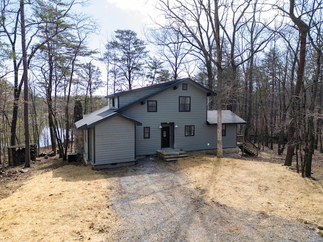 view of front of property with crawl space, central AC, driveway, and a chimney