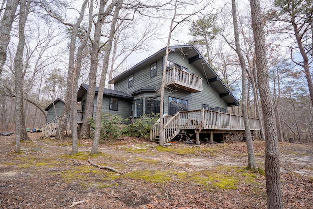 rear view of property featuring a balcony and stairs