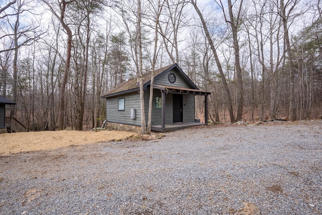 view of outbuilding featuring covered porch and a view of trees