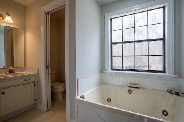 bathroom with a jetted tub, toilet, a wealth of natural light, and vanity