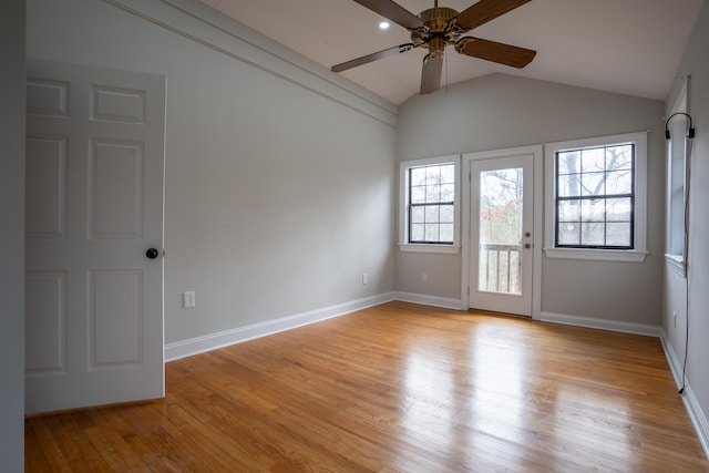 empty room featuring lofted ceiling, baseboards, a ceiling fan, and light wood-style floors