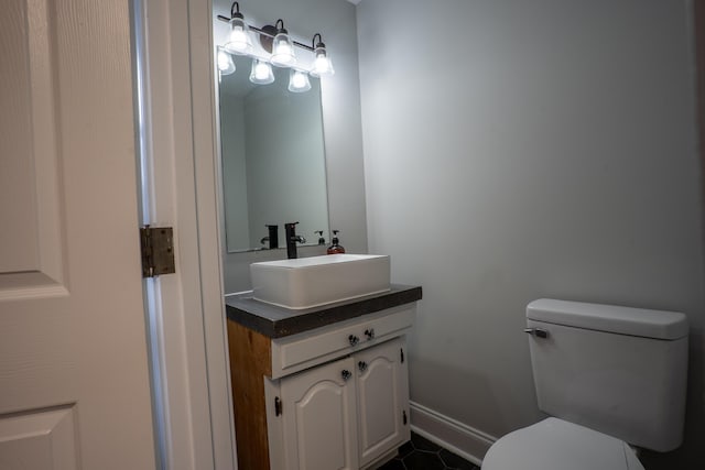 half bath featuring toilet, baseboards, and vanity