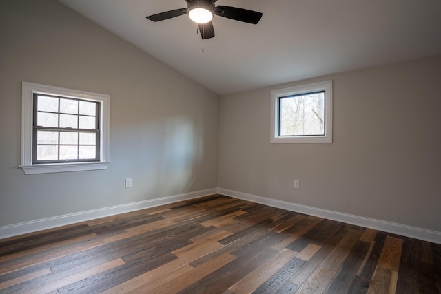 unfurnished room featuring dark wood-style floors, baseboards, vaulted ceiling, and a wealth of natural light