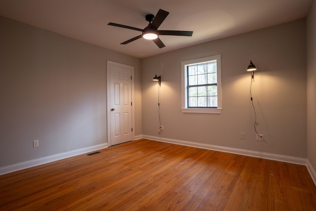 unfurnished room with a ceiling fan, baseboards, visible vents, and hardwood / wood-style floors