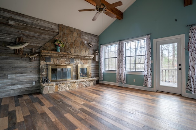 unfurnished living room featuring high vaulted ceiling, a stone fireplace, hardwood / wood-style flooring, and a healthy amount of sunlight