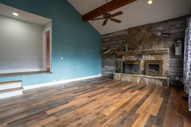 unfurnished living room with beamed ceiling, a stone fireplace, baseboards, and hardwood / wood-style flooring