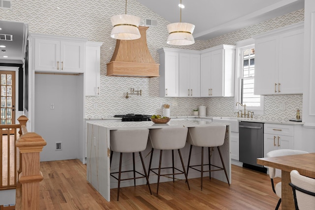 kitchen with light wood finished floors, stainless steel dishwasher, white cabinets, and a center island