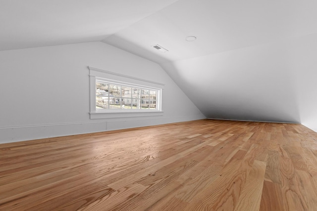 bonus room with vaulted ceiling, wood finished floors, and visible vents