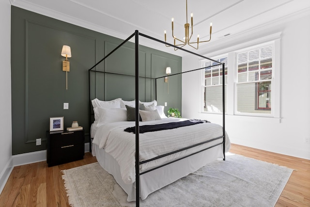 bedroom with visible vents, an inviting chandelier, ornamental molding, wood finished floors, and baseboards