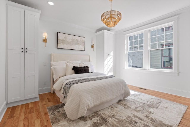 bedroom featuring recessed lighting, visible vents, baseboards, light wood-style floors, and ornamental molding