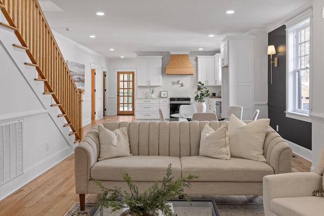 living area featuring visible vents, light wood-style flooring, stairway, ornamental molding, and recessed lighting