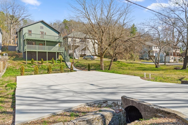 exterior space featuring stairs, concrete driveway, and a yard