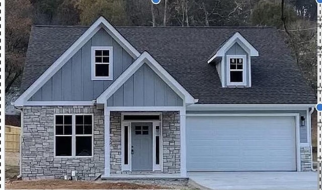 view of front of property featuring board and batten siding, concrete driveway, and stone siding